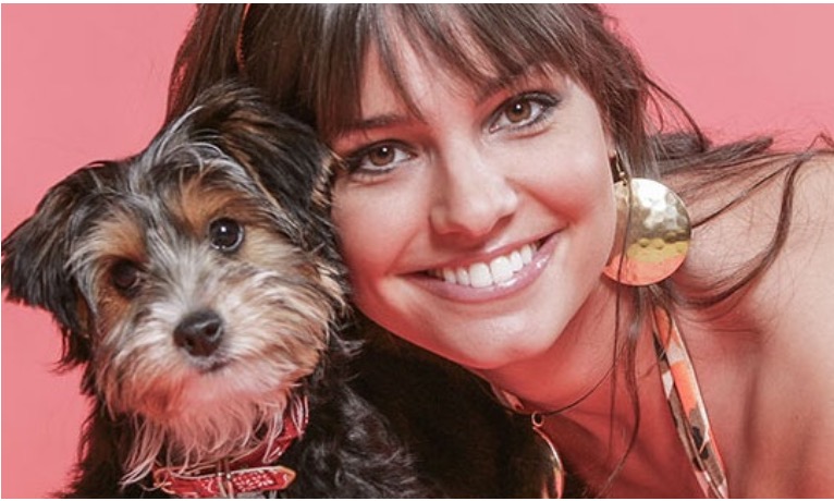 Young woman with her dog against her cheek